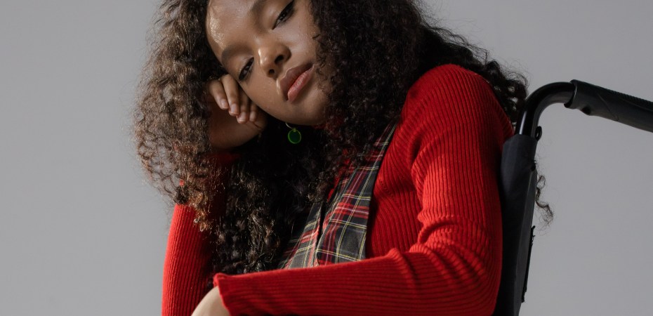 Person in red shirt sits patiently in a wheelchair while someone tries to figure out what they should have access to